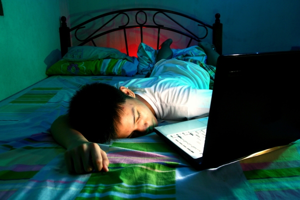 床上看電腦睡著的小男孩
