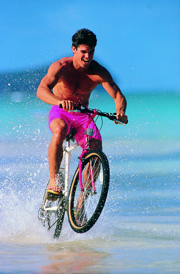 海滩上骑自行车的外国男士图片