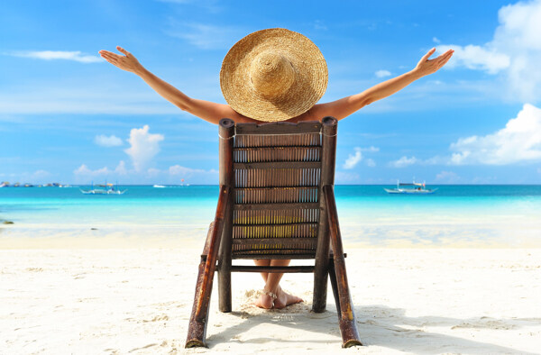 坐在椅子上在沙滩上晒太阳的美女背影图片